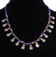 Collier ethnique artisanal perles bleues agencees de tubes en bois, agremente de petites breloques tourbillon en metal argente